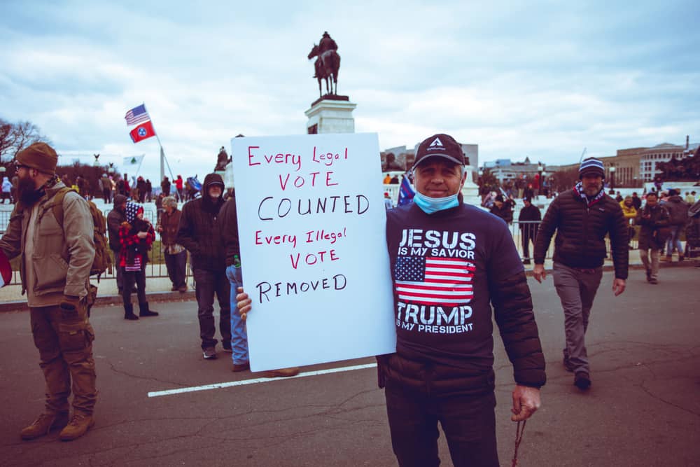 Protestor showing a sign that says "Every Legal vote COUNTED. Every illegal vote removed."