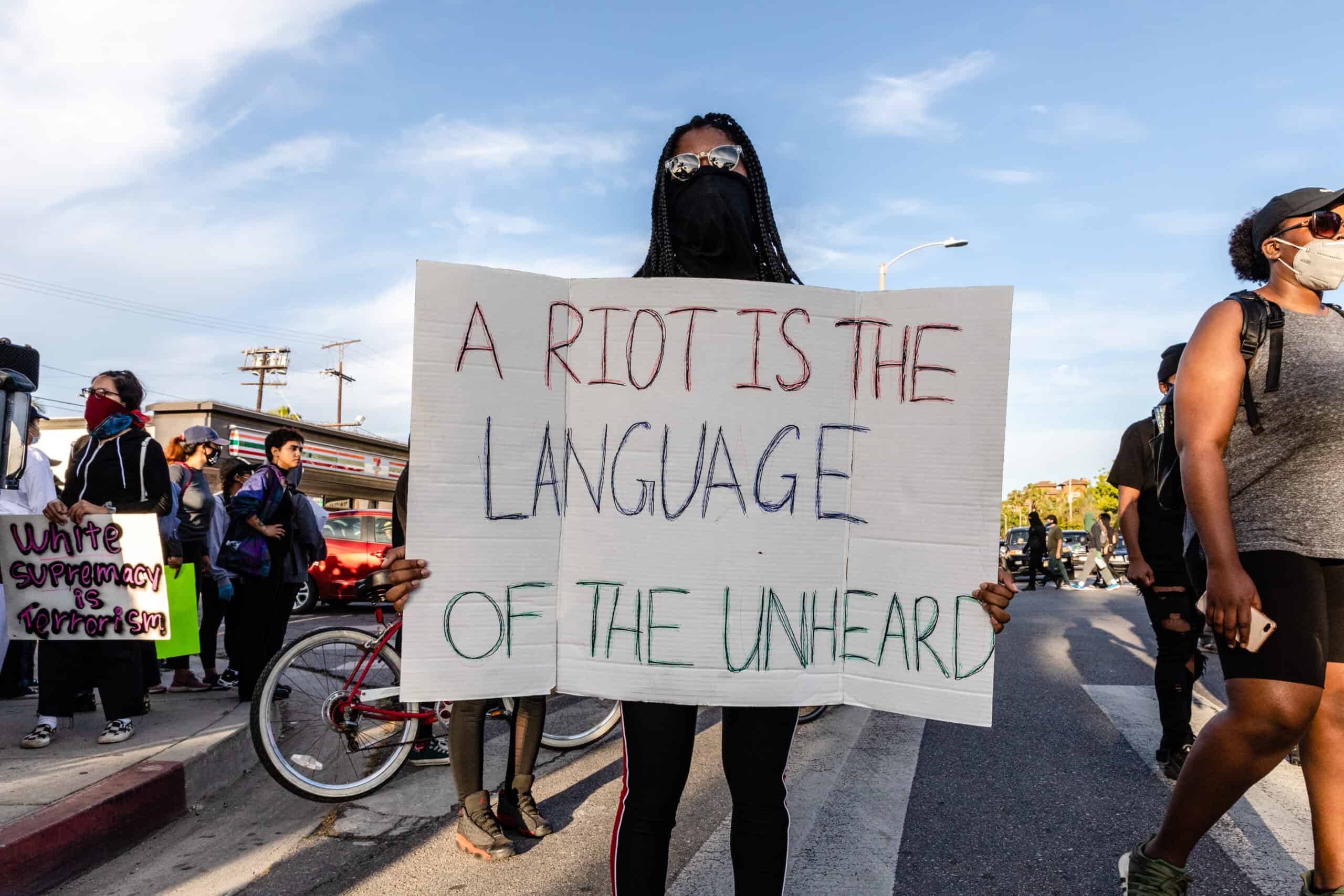 Protestor holding sign that says A Riot is the Language of the Unheard