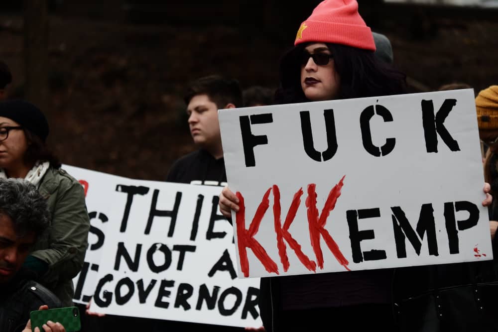 Protester holding sign saying "FUCK KKKEMP"