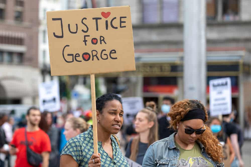 Woman holding a sign that says "Justice for George"