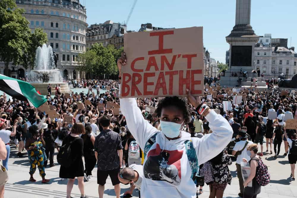 Black Live Matter Protestor raising a sign that says "I Can't Breathe"