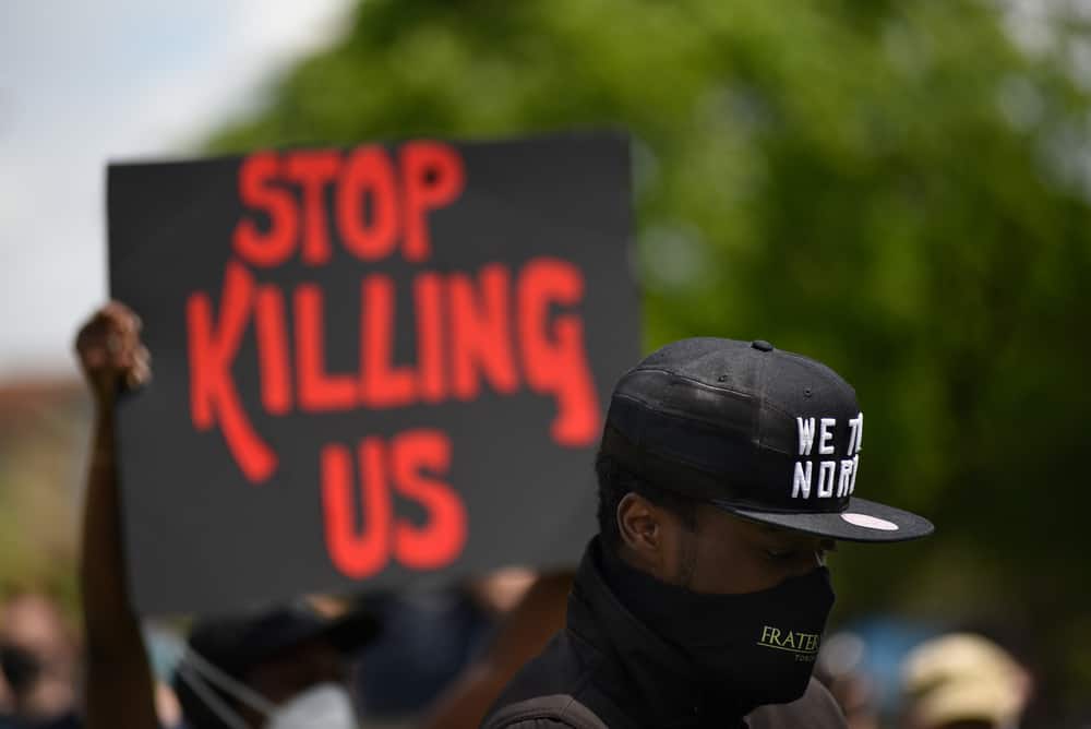 Protestor holding a sign saying Stop Killing Us