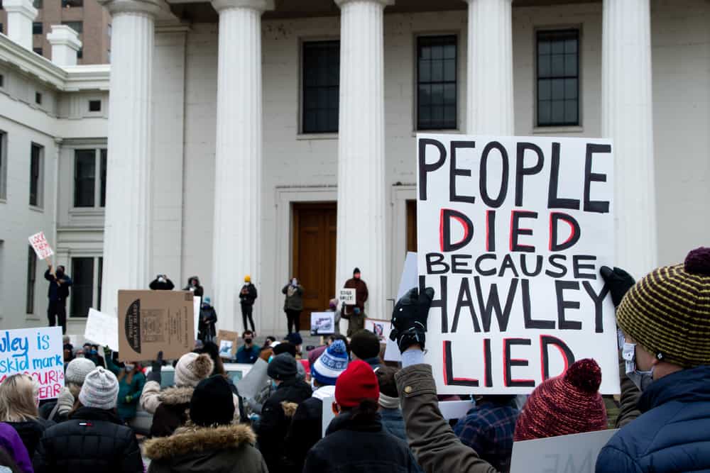 Sign being held up stating "People died because Hawley Lied"