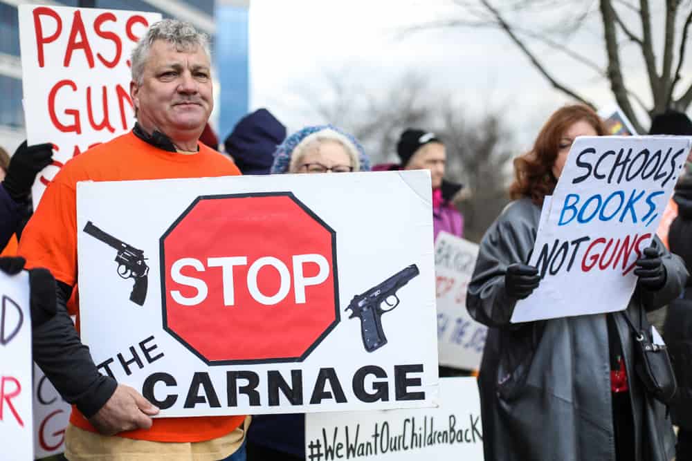 Man holding a sign that says "Stop the Carnage"