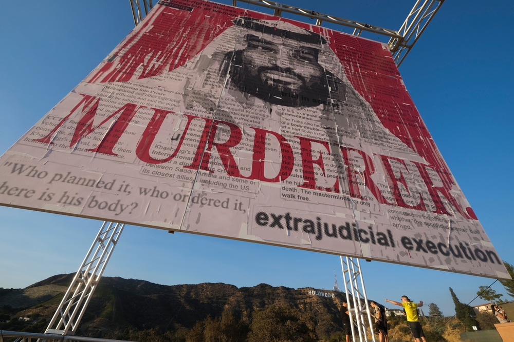 Sign being held up of MBS stating MURDERER