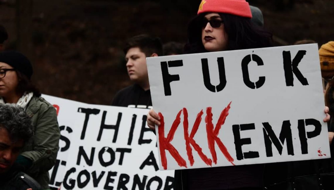 Protester holding sign saying "FUCK KKKEMP"