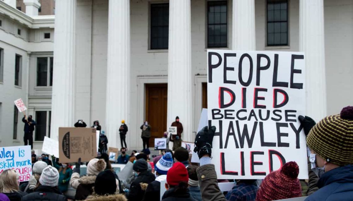 Sign being held up stating "People died because Hawley Lied"